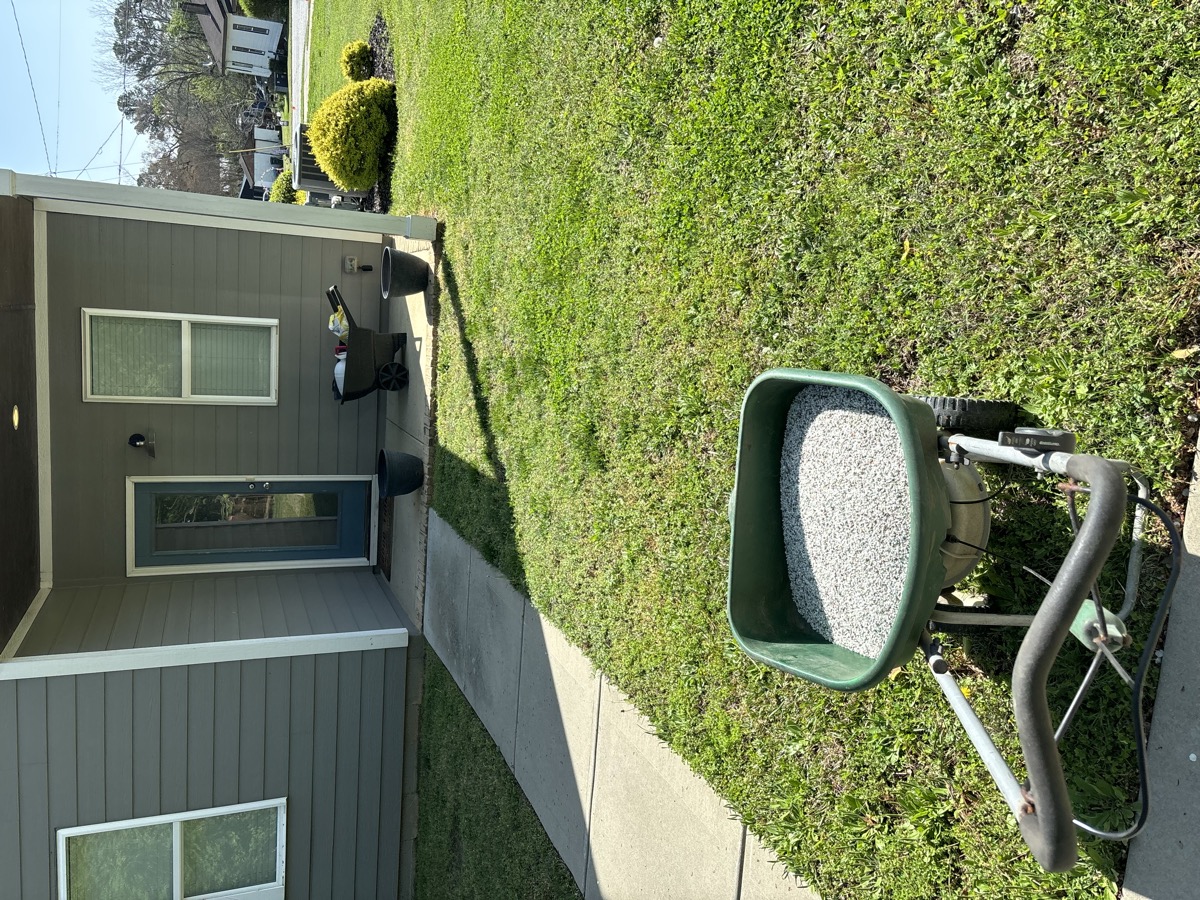 Fertilizer spreader treating lawn at residential property